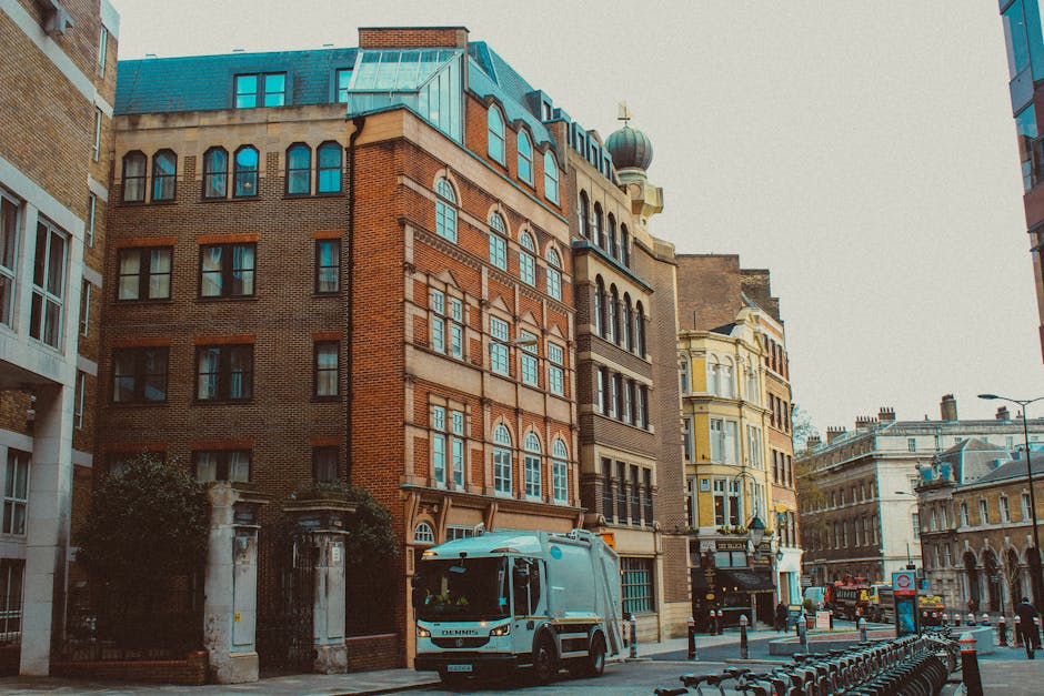 A tall, multi-storey building made of brown brick with ornate architectural details illuminated by exterior lighting during dusk. Multiple laundry clothes in various colors, including white, pink, gre