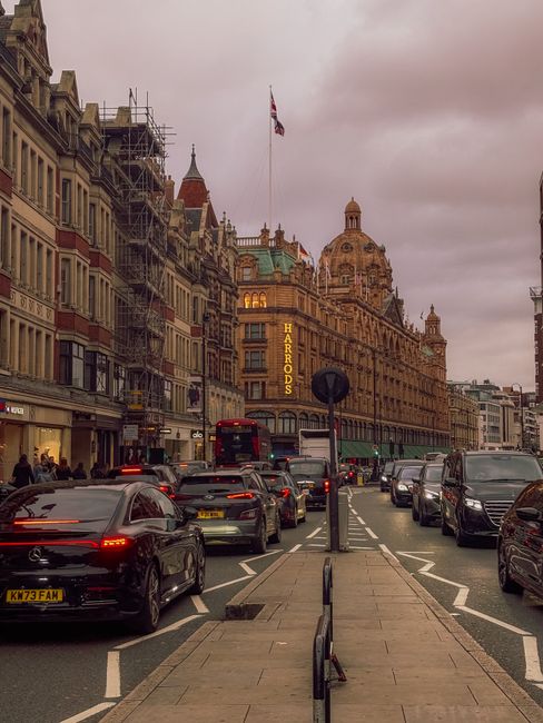 A white commercial van belonging to Man with Van Knightsbridge is parked on a city street, adjacent to a building with large arched windows and a green rooftop. The van is positioned next to a buildin