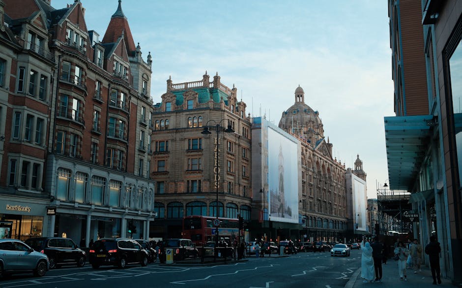 A street scene in Knightsbridge shows a building with an orange awning and large windows, with a small balcony and decorative railing at the sidewalk level. In front of the building, there is a busy l